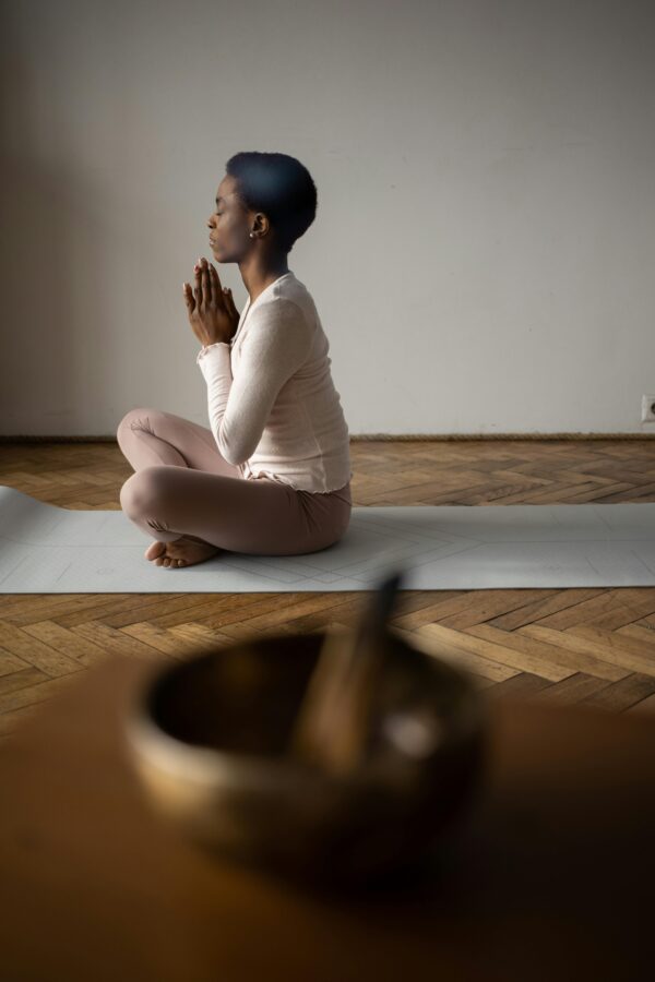 Woman meditating on yoga mat indoors, focusing on mindfulness and tranquility.