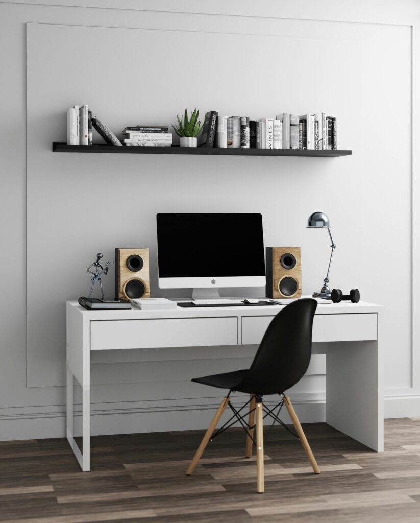 Sleek modern home office setup with computer, speakers, and decor elements on a white desk.